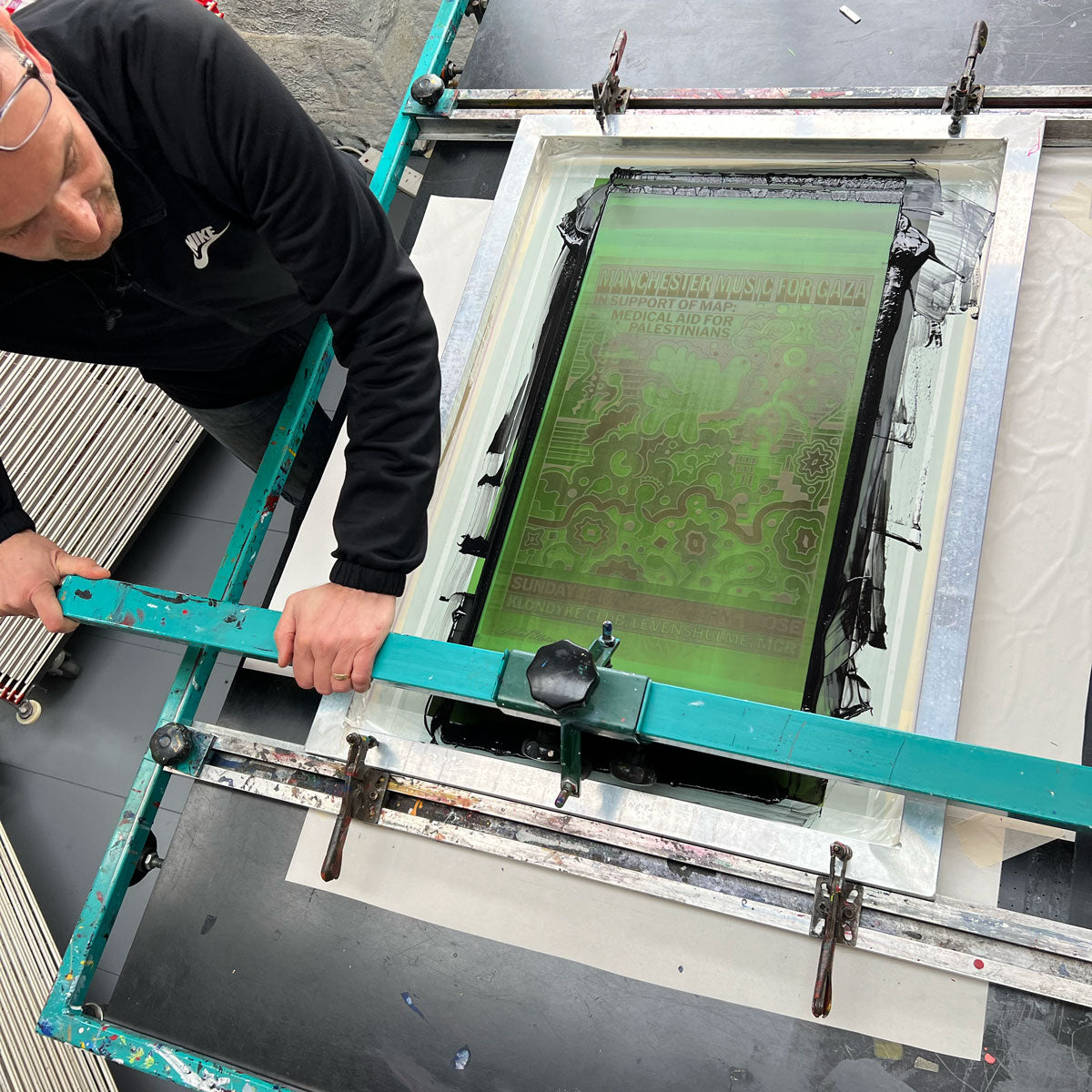 Screenprinter hand printing posters on a printing press
